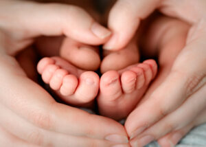 10 tiny baby toes held by parents hands