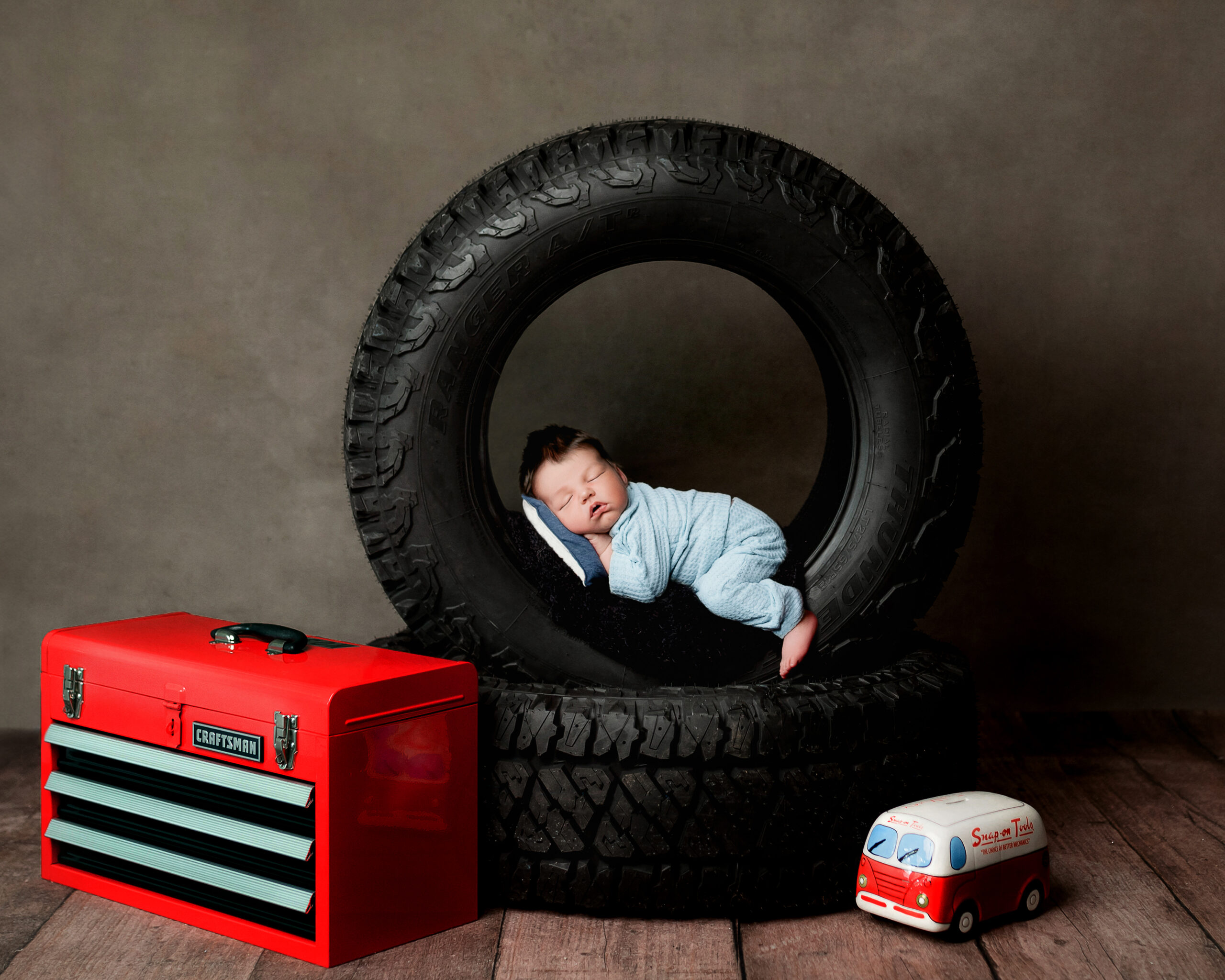 newborn baby laying inside of a tire, mechanics baby