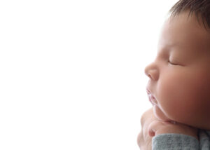 side profile of baby on white background sleeping