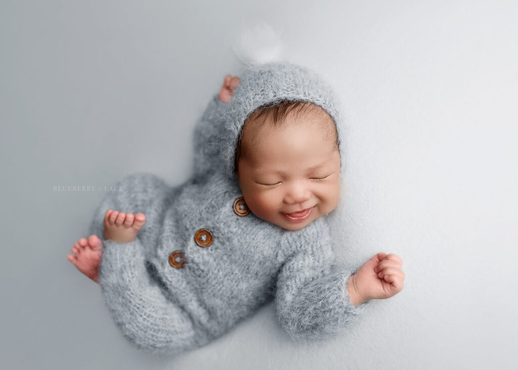 baby boy dressed in winter blue outfit smiles for photo