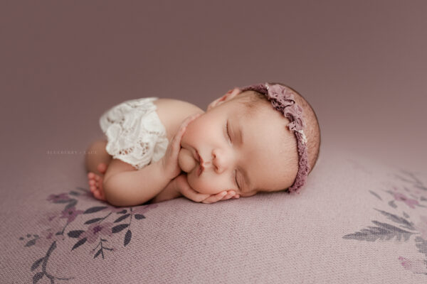 Newborn baby in purple in timber pose at photo studio