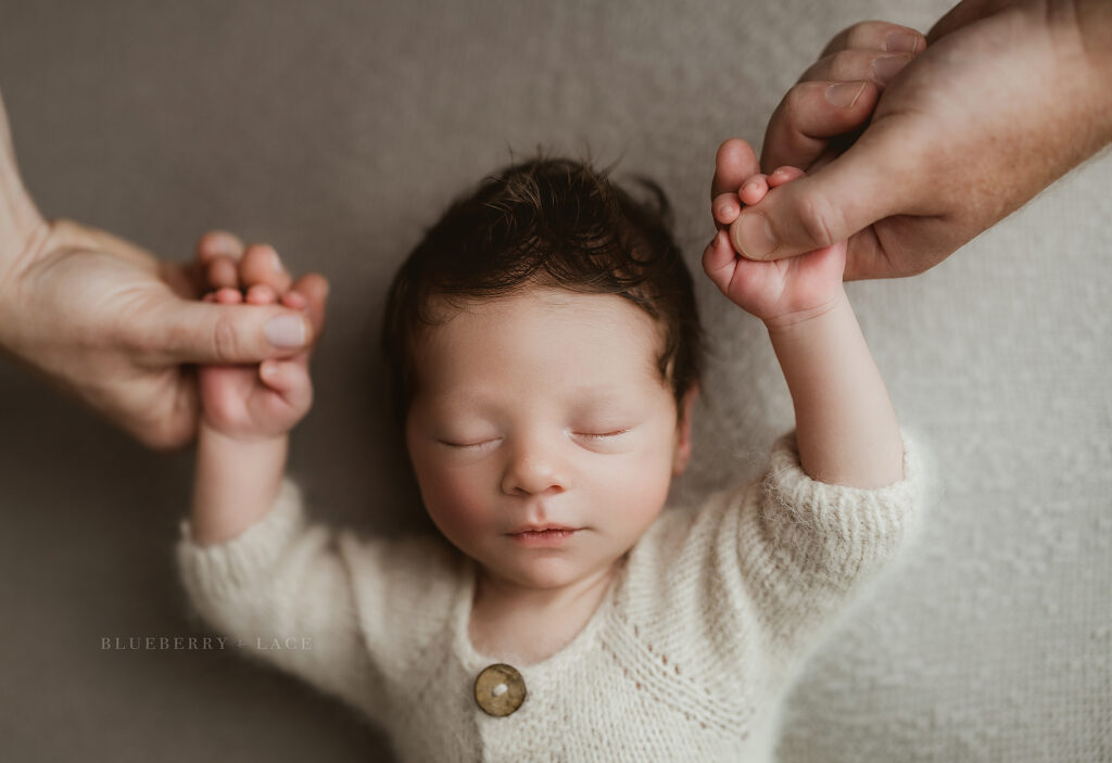 Holding hands with parents during newborn photoshoot